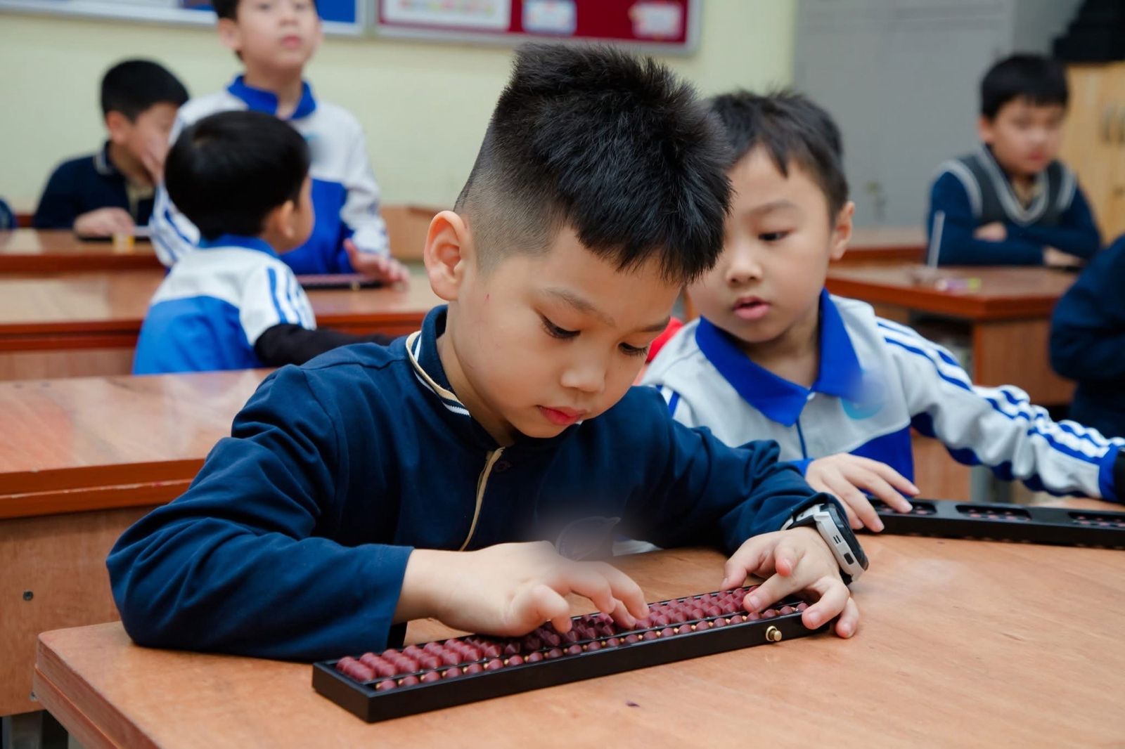Một bạn nhỏ đang tập trung gảy bàn tính Soroban trong giờ học
