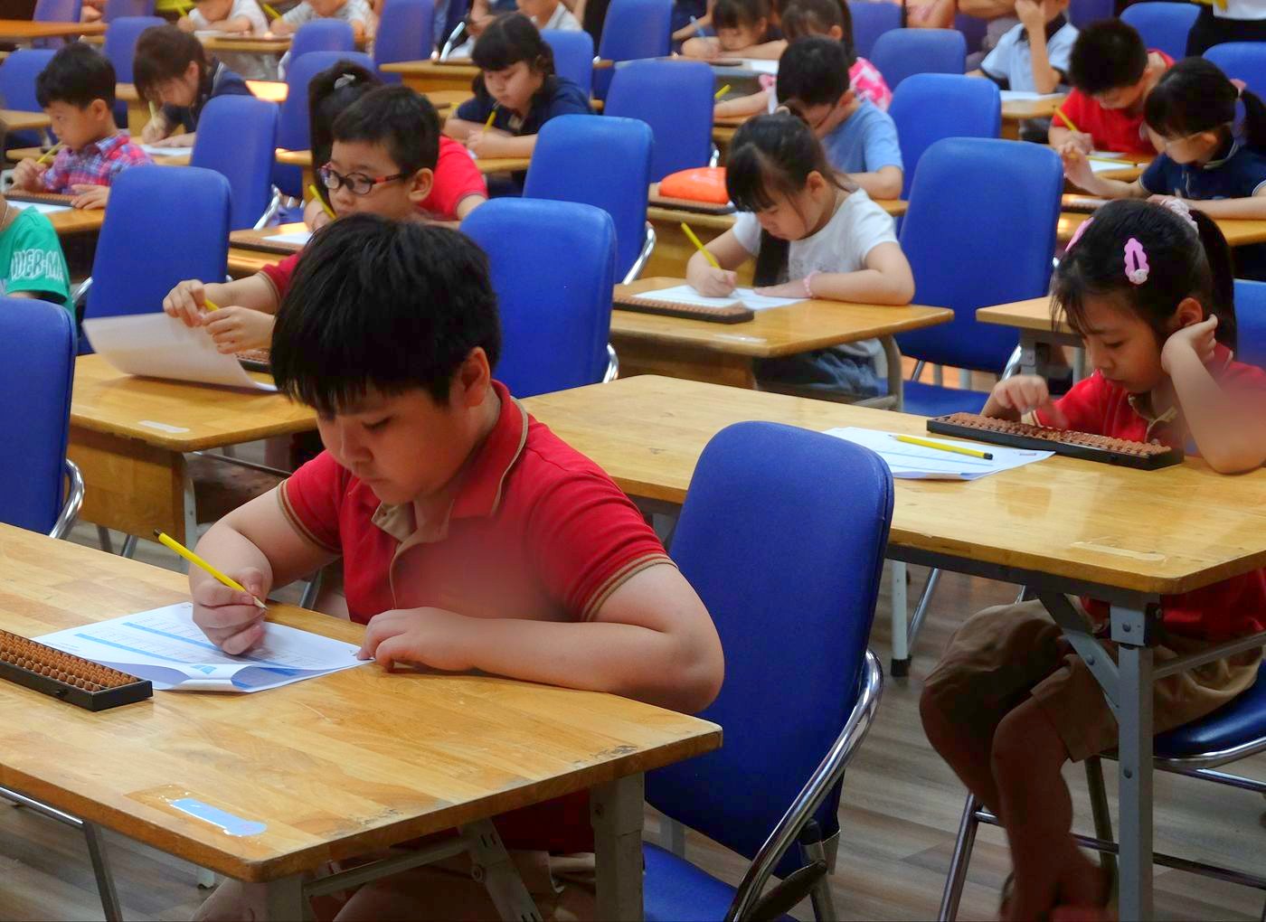 Các bạn nhỏ làm bài thi tính nhẩm bên bàn tính tại Soroban SmartMath Cup 2025