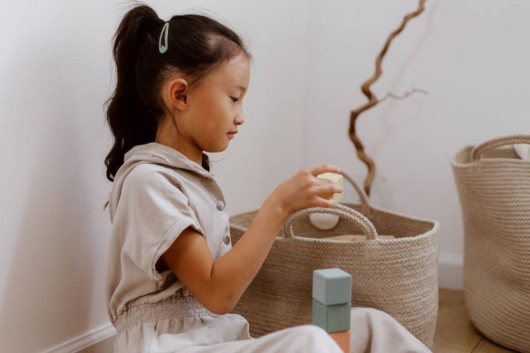 女の子が自分でおもちゃをかごにしまっている