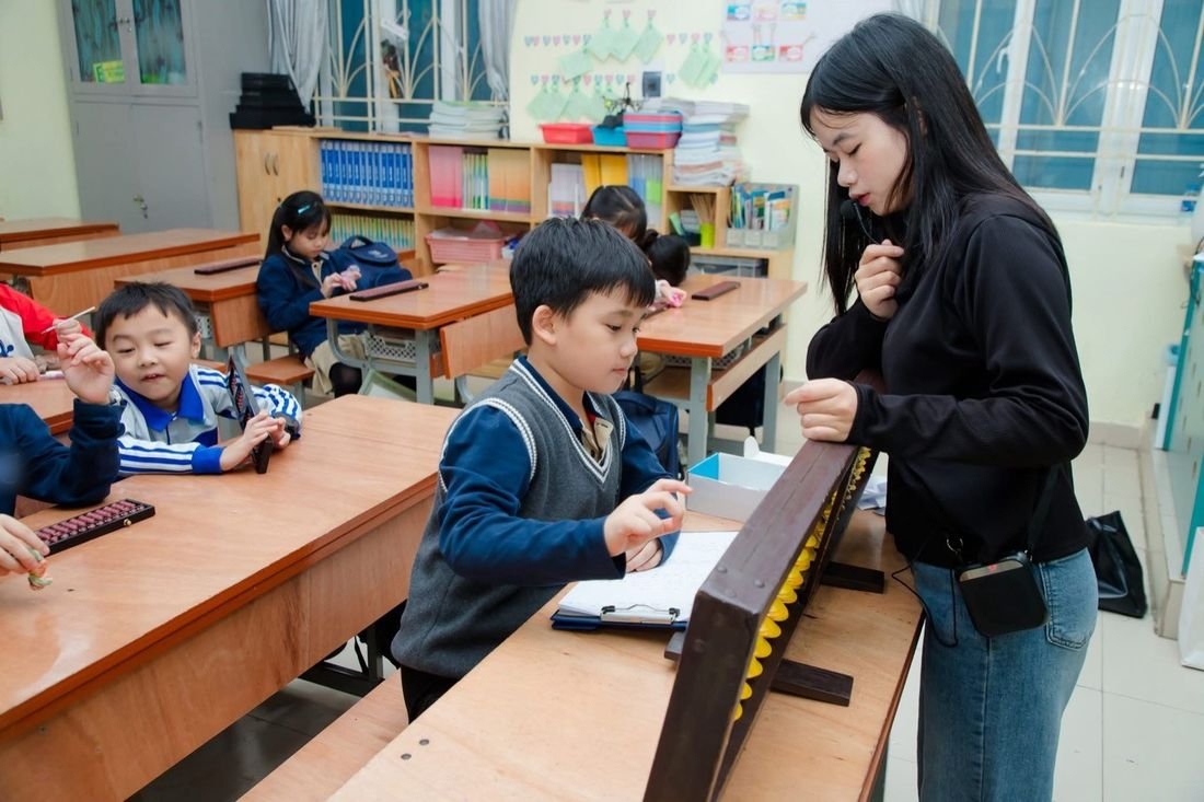 Giáo viên hướng dẫn một bạn nhỏ gảy bàn tính